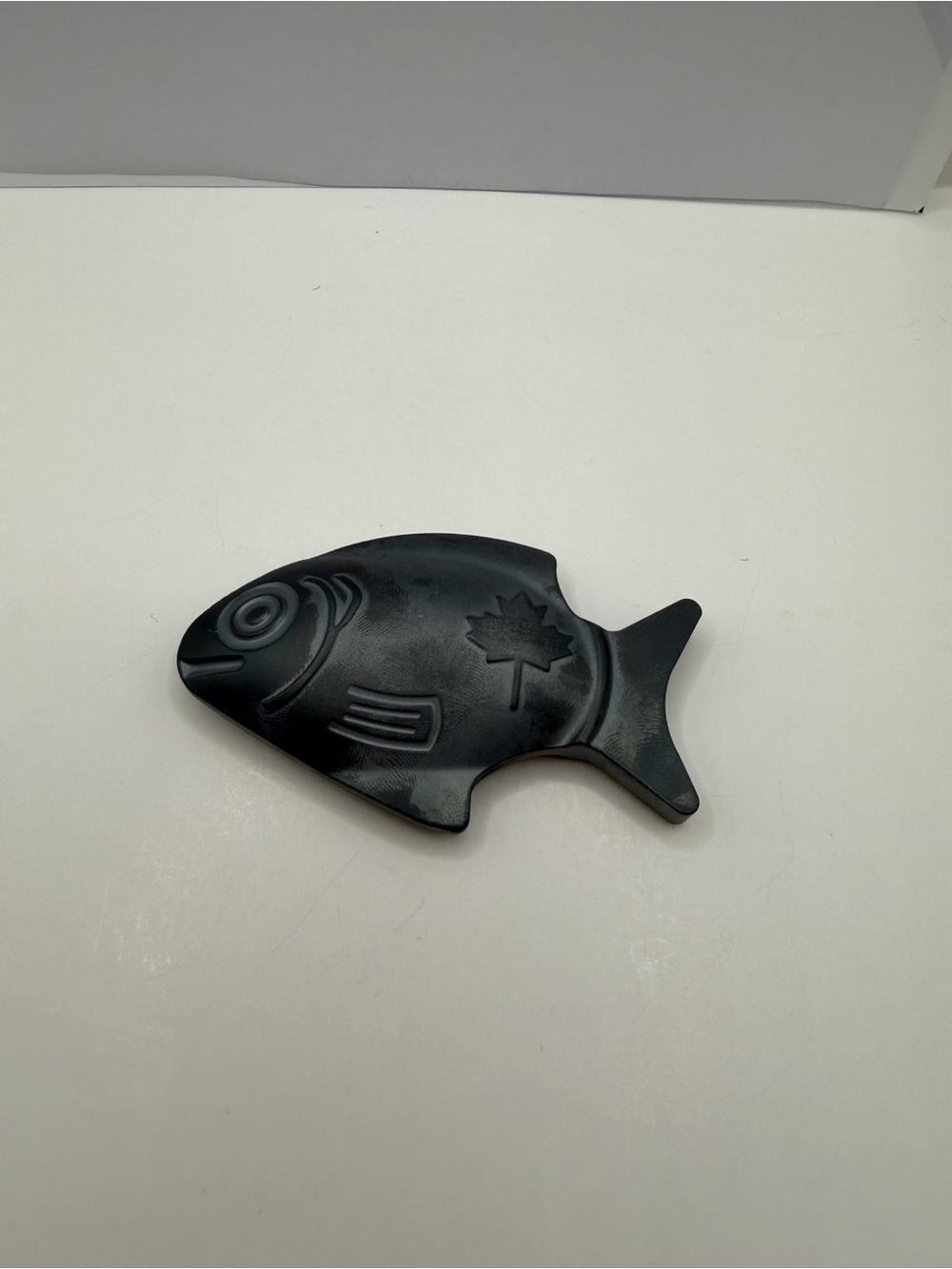 fish-shaped stone with carved maple leaf and lines